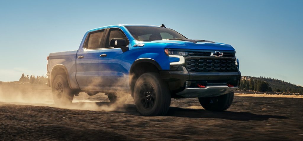2026 Chevrolet Silverado in motion on rugged terrain, showcasing a bold exterior and capable interior designed for off-road driving