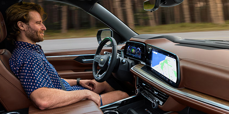 A man in the driver's seat of a car, hands on the steering wheel, ready to drive.