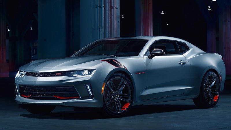 People enjoying a sunny day next to a green Chevy Trax parked near scenic hills