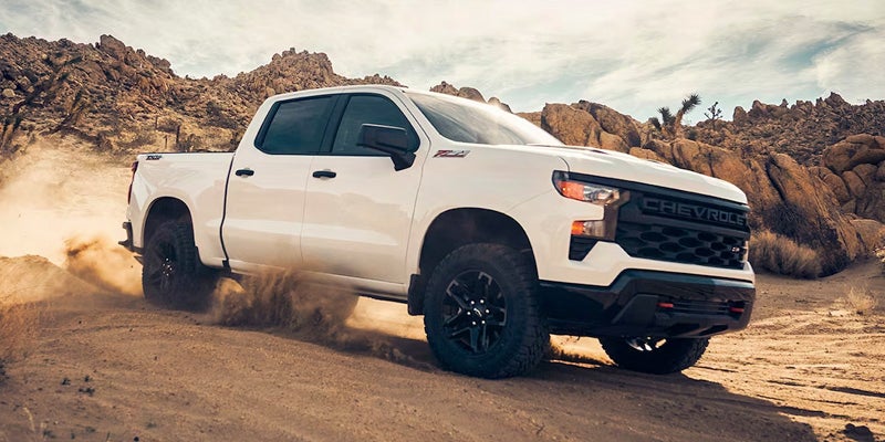 White Chevrolet Silverado 1500 kicking up dust on a rugged desert trail