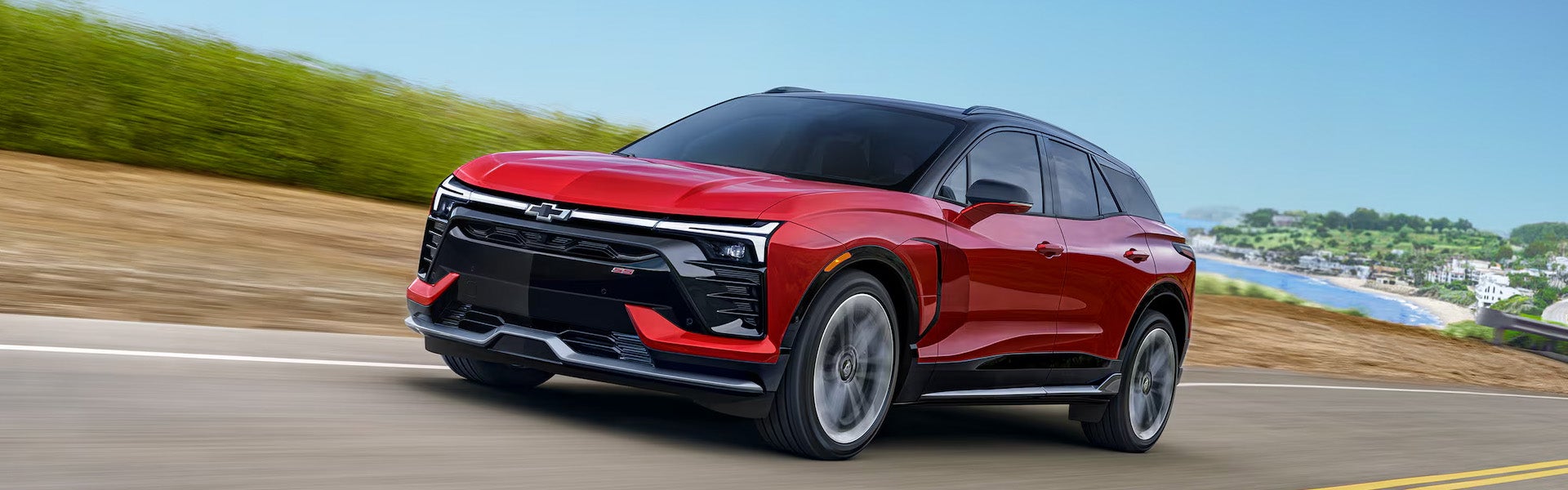 A 2026 Chevrolet Blazer EV driving along a scenic road, showcasing its sleek design and modern features